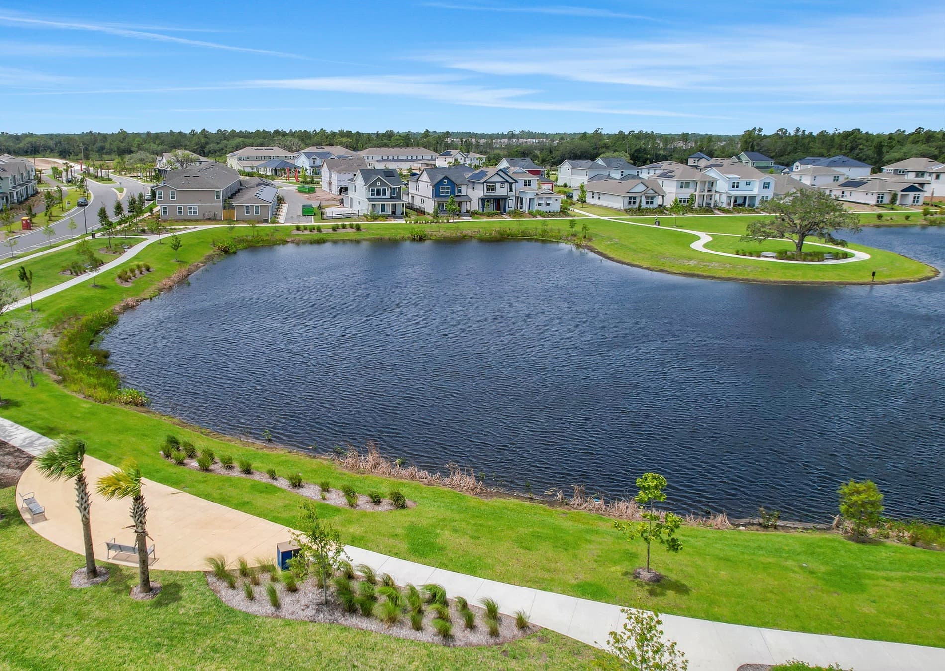 Vista aérea de Weslyn Park at Sunbridge: lago, senderos y viviendas nuevas en St. Cloud, Florida